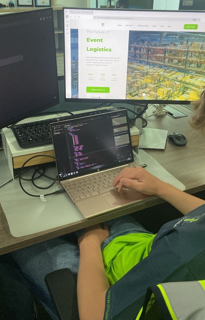 Will Hanlon working on a laptop connected to external monitors while building an event logistics interface during placement.